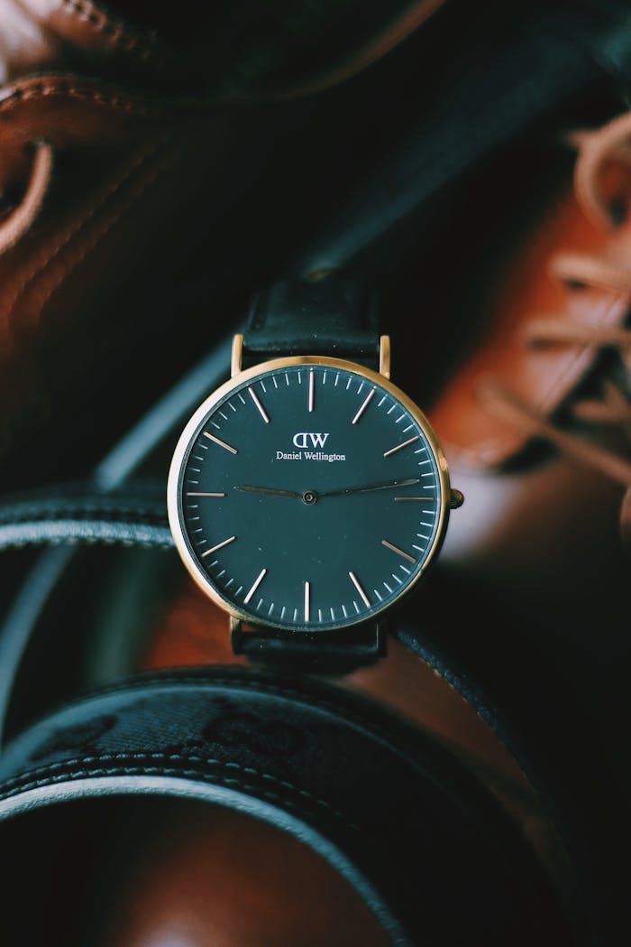 Close-up of a sleek wristwatch surrounded by leather accessories, highlighting timeless elegance.