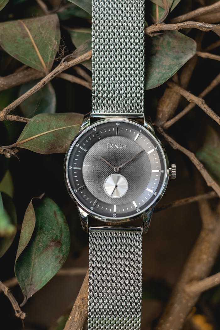 Elegant watch with Milanese strap amidst twigs and leaves in a serene outdoor setting.
