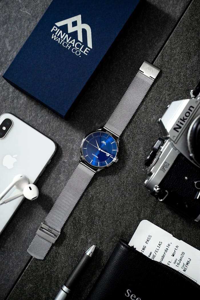 Stylish flat lay showcasing technology devices, watch, and accessories on dark surface.